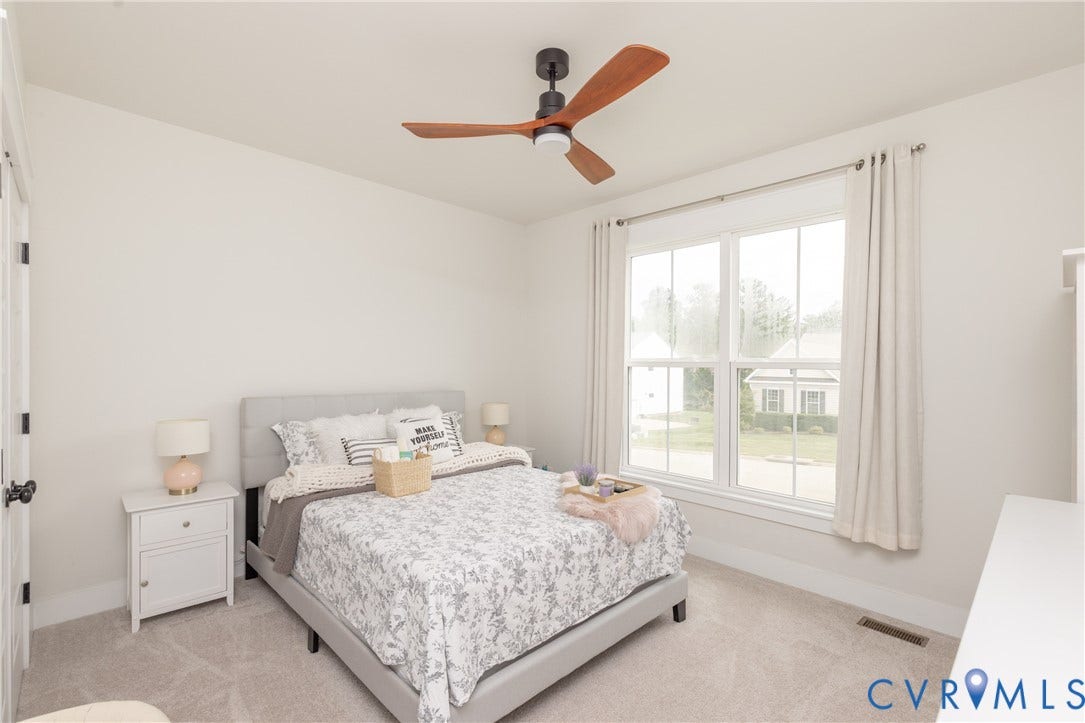 Vaulted ceiling with a wood-finish ceiling fan, large double-hung window, light-toned carpet flooring, and white trim throughout