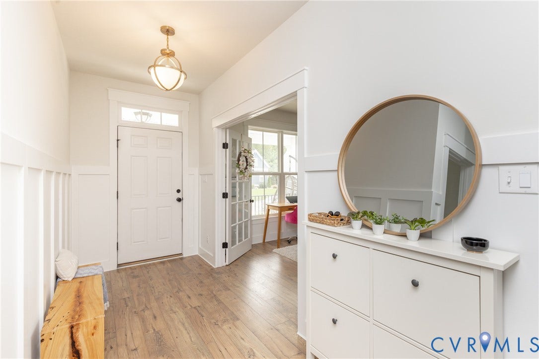 Entryway featuring wood-finish flooring, white paneled wainscoting, and a ceiling-mounted light fixture
