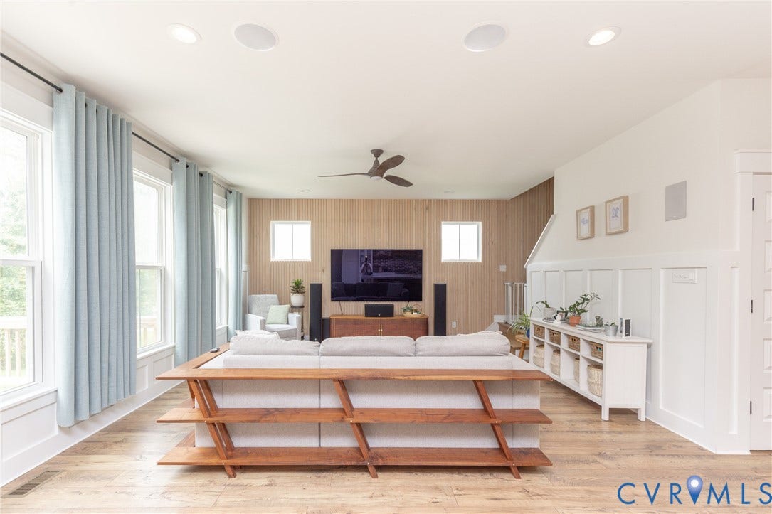 Recessed ceiling lighting, wood-finish flooring, accent wall with vertical wood paneling, multiple windows, and a ceiling fan