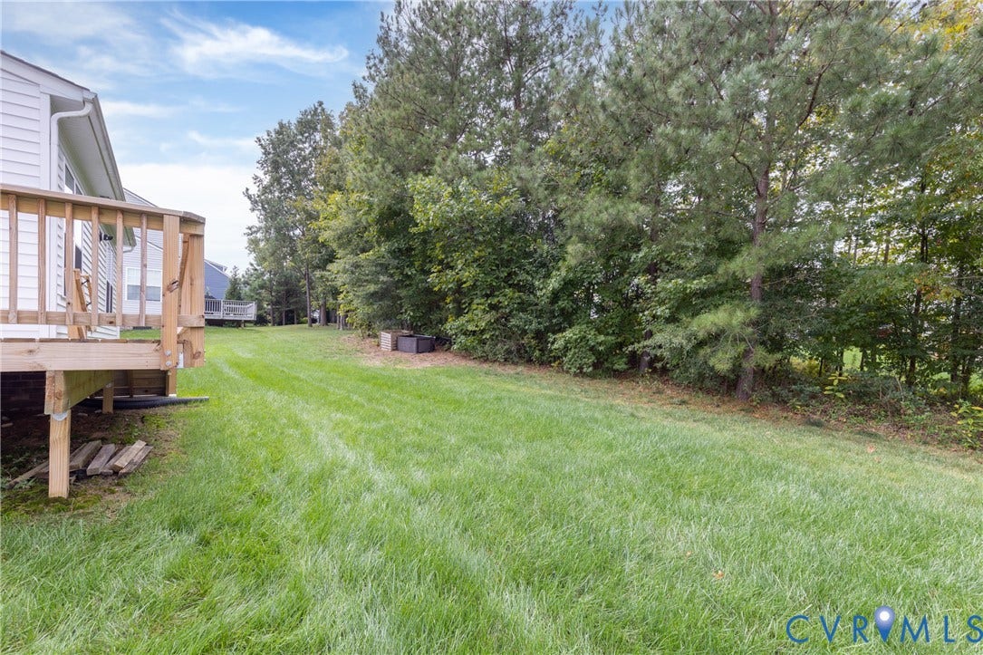 Expansive green lawn with mature trees and a wood deck
