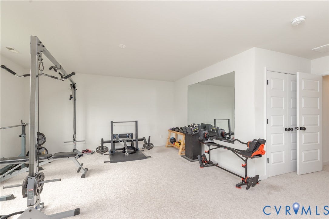 Light-colored carpeting, white walls, recessed lighting, and a full-wall mirror