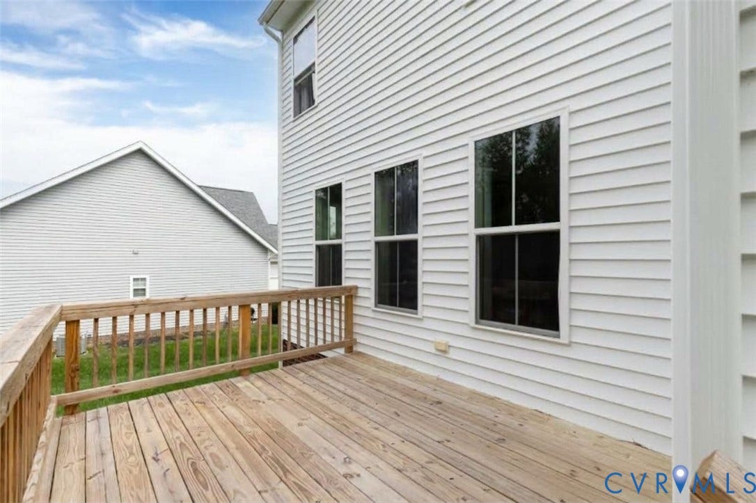 Wood deck with a natural finish, wood railing, and white horizontal siding