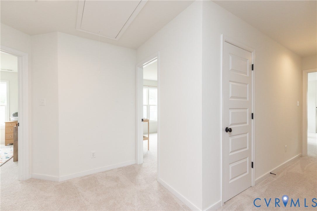 Light-toned wall finishes, paneled interior doors with matte black hardware, recessed lighting, and soft carpet flooring
