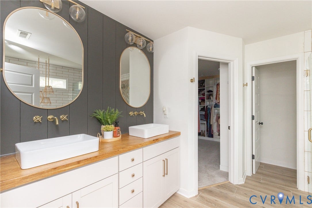 Double vanity with wood-finish countertop, dual vessel sinks, and gold-finish wall-mounted faucets