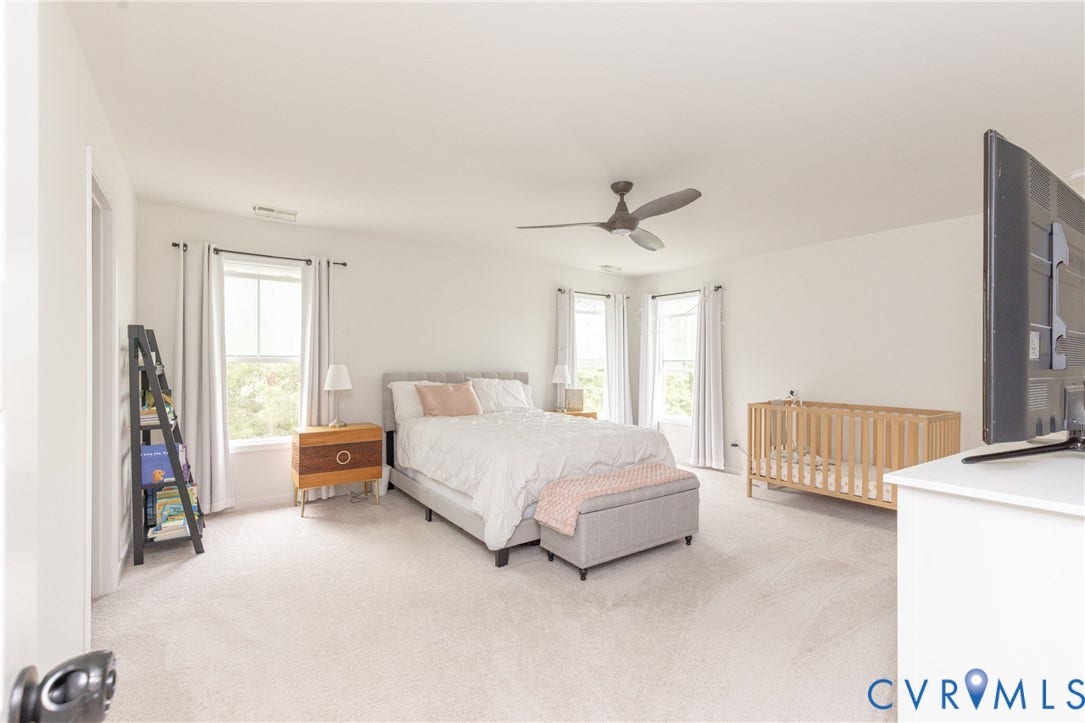 Bright room featuring multiple windows, a ceiling fan, and light-toned carpeting
