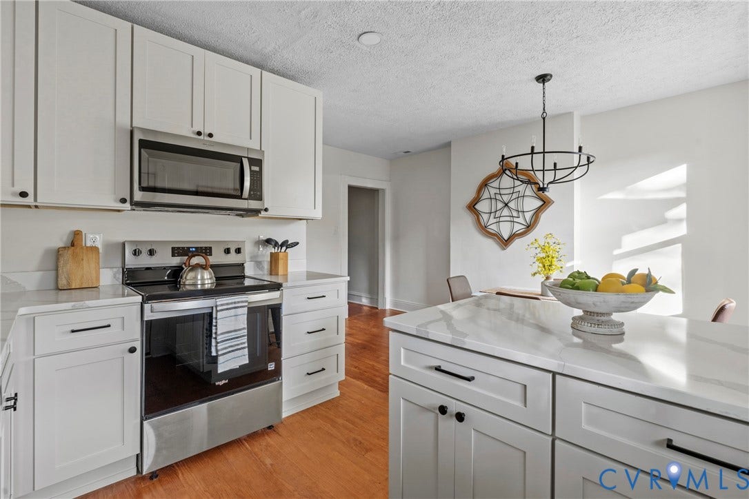 2931 W Leigh Street, Scotts Addition, Richmond, VA 23230 White shaker cabinetry, stainless steel appliances, solid surface countertops, a center island, and wood-finish flooring