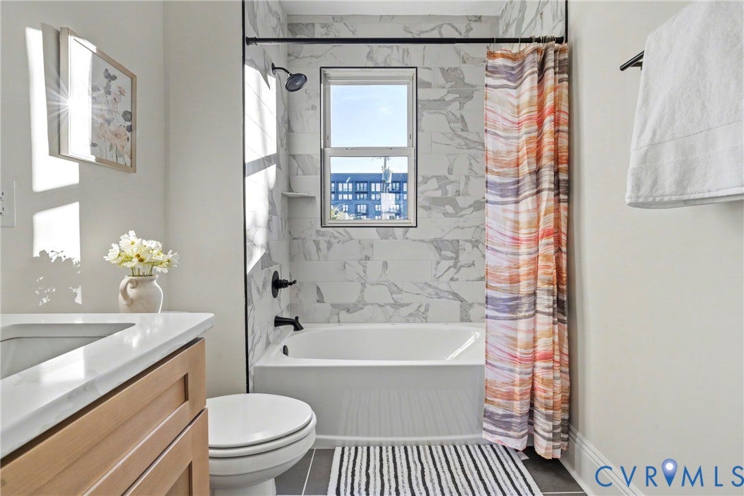 2931 W Leigh Street, Scotts Addition, Richmond, VA 23230 Bathtub with white subway tile surround, dark plumbing fixtures, and a window