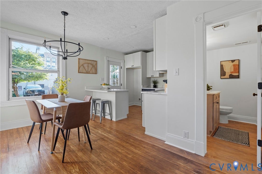 2931 W Leigh Street, Scotts Addition, Richmond, VA 23230 Hardwood-finish flooring, white trim, white cabinetry, light-toned countertops, and a contemporary black chandelier