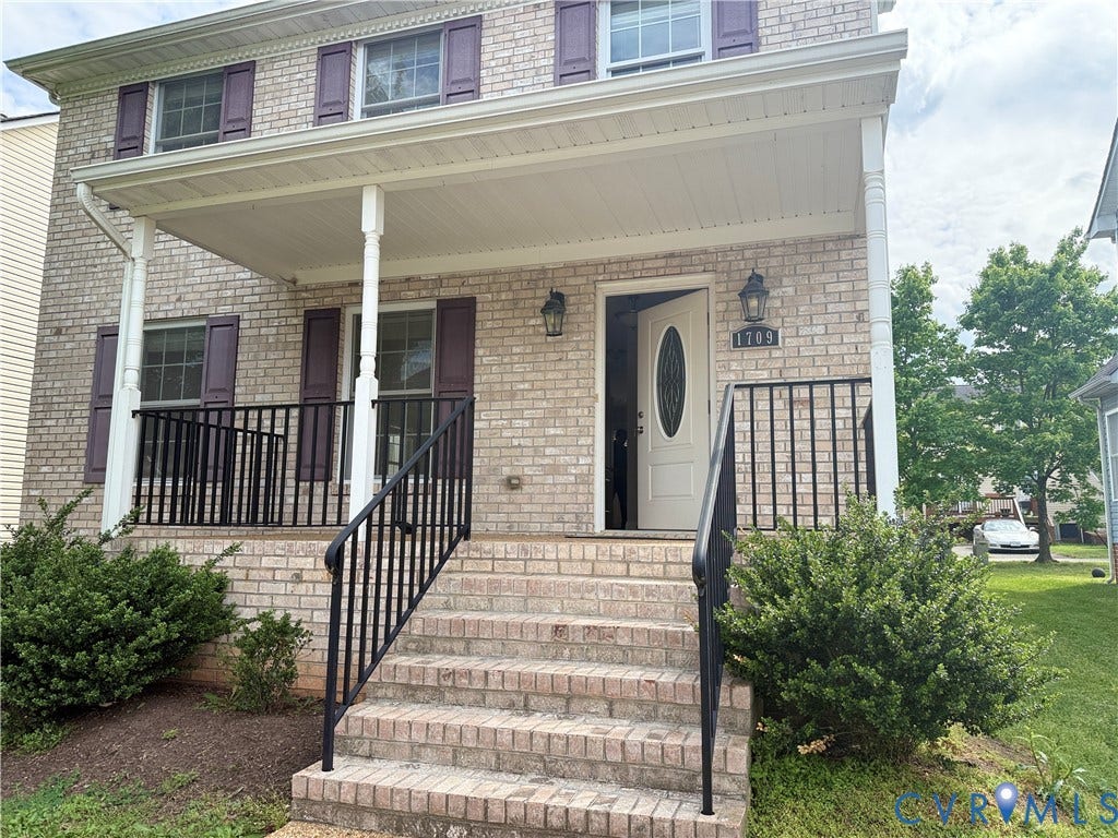 1709 Kemper Street, Richmond, VA 23220 Brick facade featuring a covered porch, white columns, decorative shutters, and a front entry door with an oval glass insert