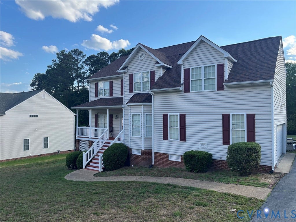Two-story residence featuring light-colored siding with contrasting shutters, a covered front porch with white railings, and a side-entry garage