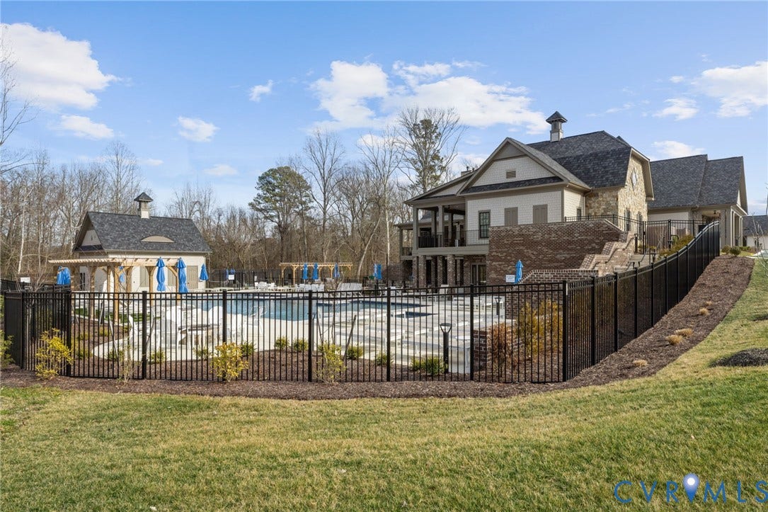 15750 Mosaic Creek Boulevard, Henrico, VA 23238 Community pool with a black metal fence, a stone and stucco clubhouse, and an adjacent pool house with a cupola