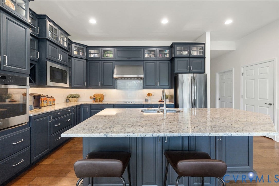 15750 Mosaic Creek Boulevard, Henrico, VA 23238 Kitchen featuring dark cabinetry, stainless steel appliances, an extra large center island with a light-toned countertop, and wood-finish flooring