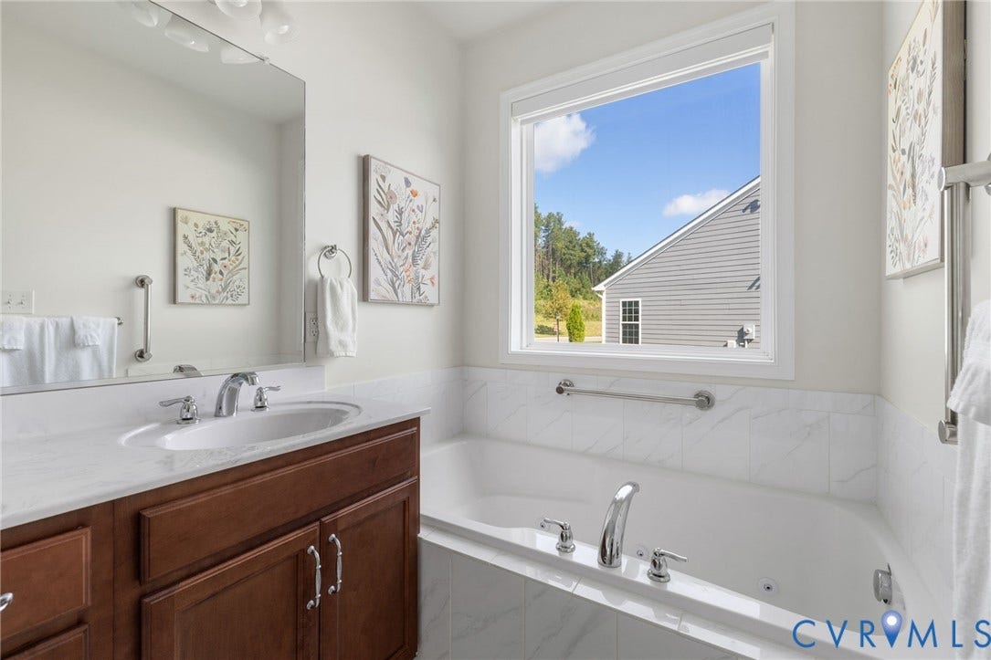 15750 Mosaic Creek Boulevard, Henrico, VA 23238 Built-in jetted bathtub with tile surround, double vanity with wood-finish cabinetry, granite countertop, and polished chrome fixtures