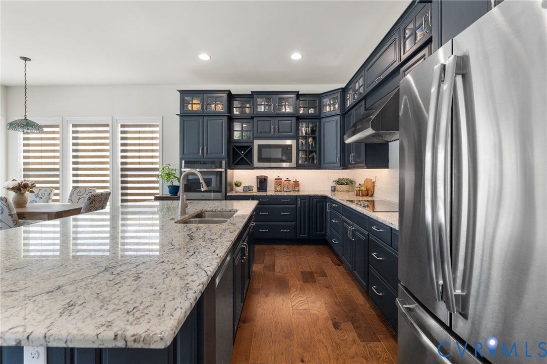 15750 Mosaic Creek Boulevard, Henrico, VA 23238 Stainless steel appliances, built-in microwave, wood-finish flooring, dark-toned cabinetry, and a spacious kitchen island with a built-in sink