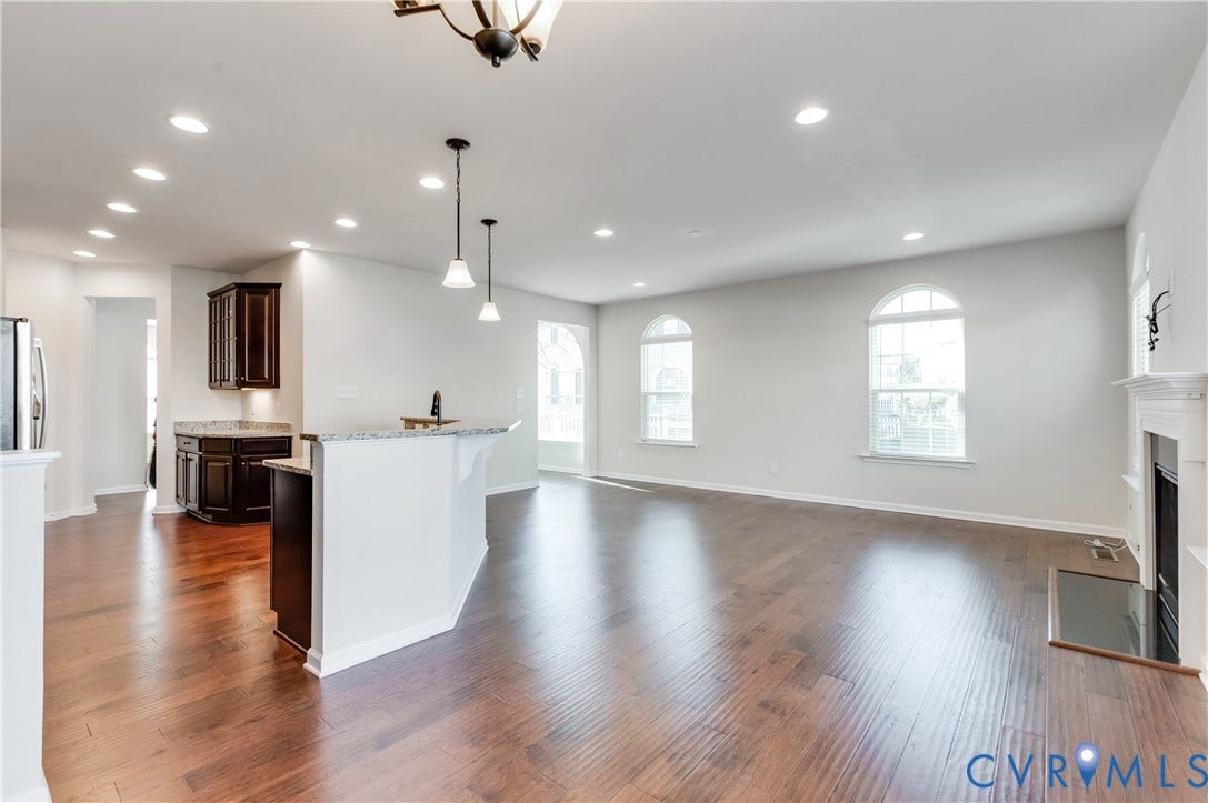 Wood-finish flooring throughout, recessed lighting, fireplace with mantel, and arched windows