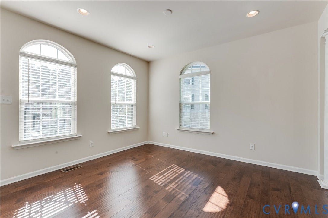 Hardwood-finish flooring, recessed lighting, and multiple arched windows with blinds