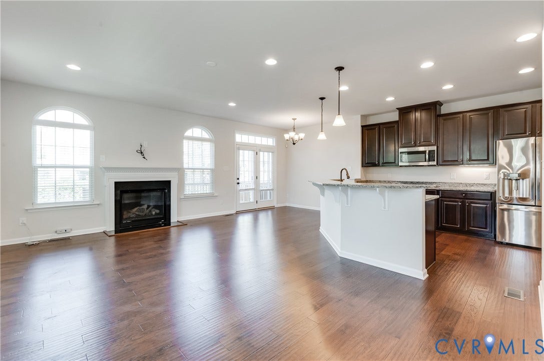 Hardwood-finish flooring throughout, kitchen with dark wood-finish cabinetry, stainless steel appliances, and a breakfast bar