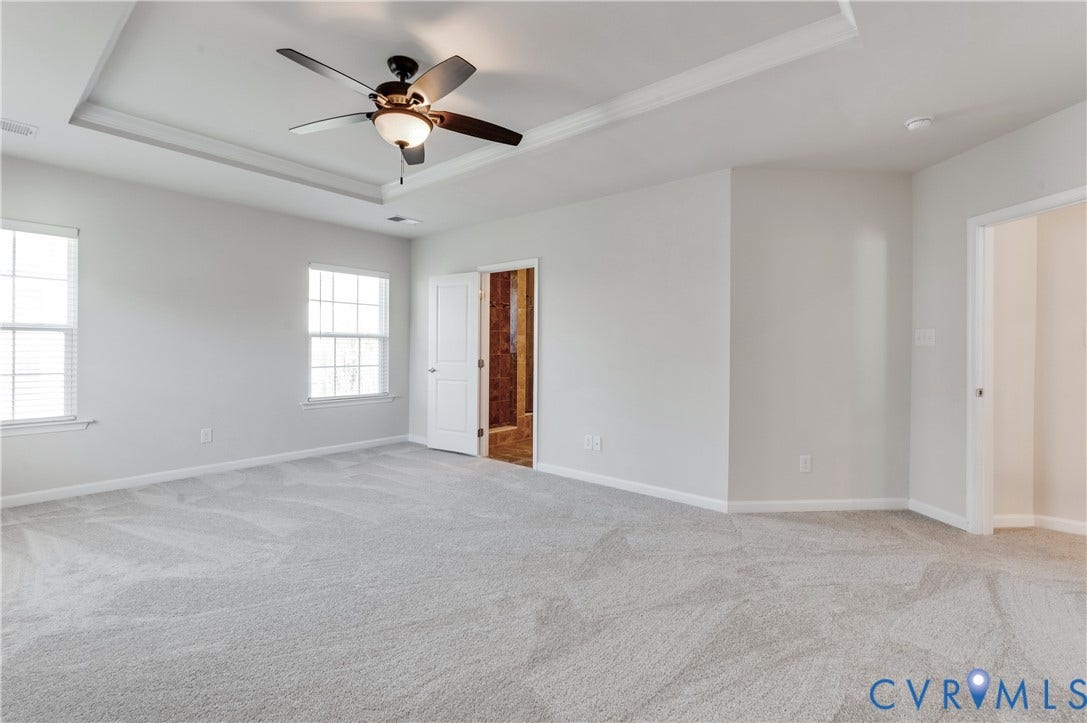 Spacious room with tray ceiling, ceiling fan, and light-toned carpet