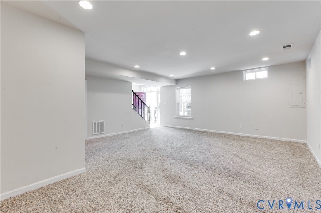 Spacious room with light-colored carpeting, recessed lighting, and white walls