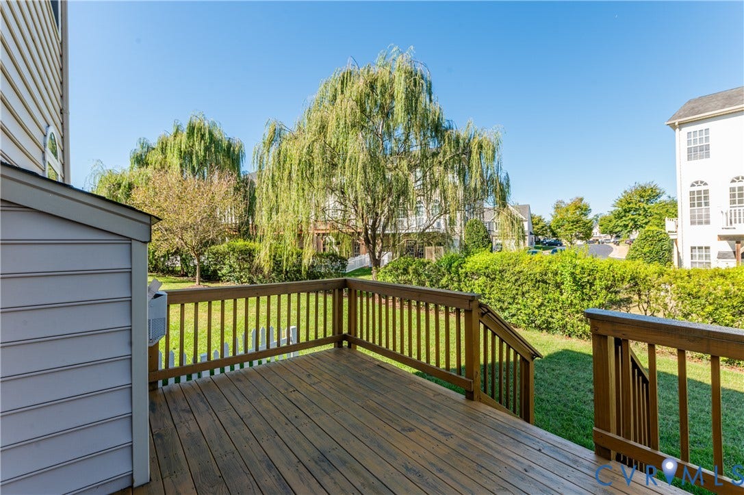 Expansive outdoor wood deck with natural wood railing, leading to a green lawn