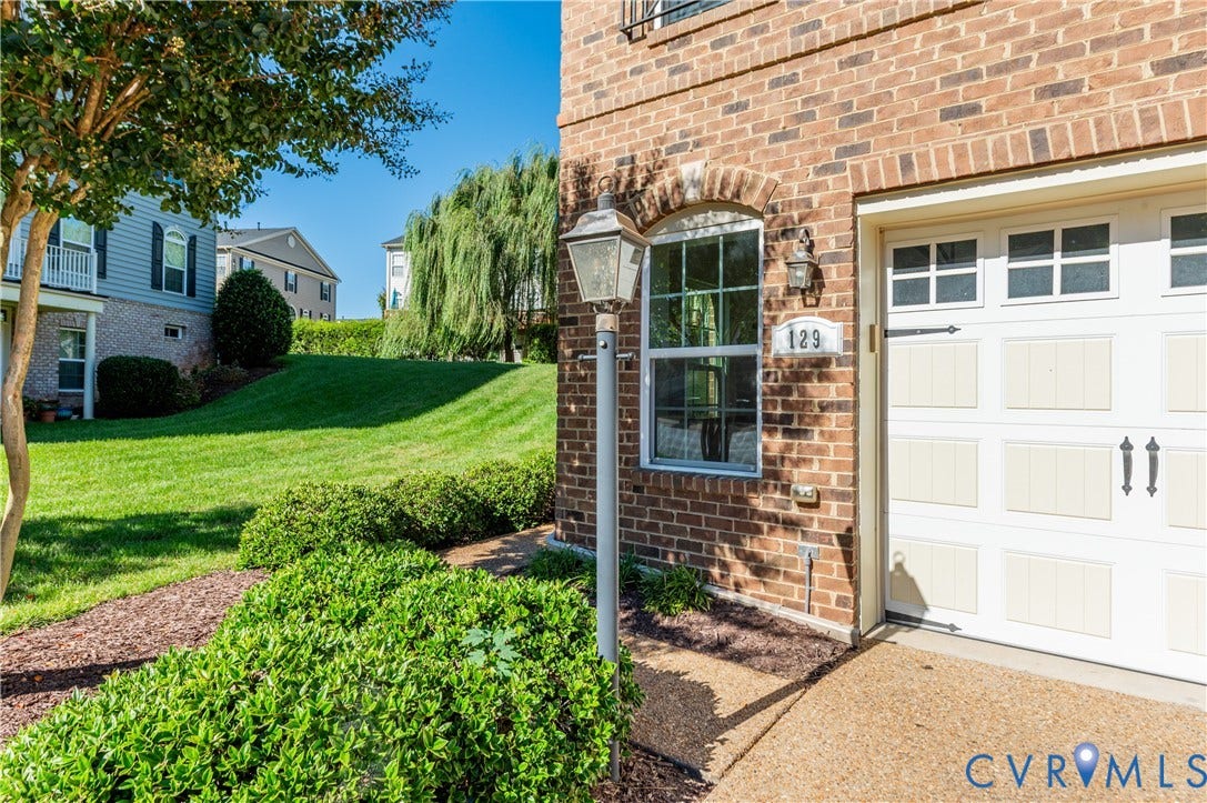 Brick exterior featuring an arched window, decorative outdoor lighting, and a white paneled garage door