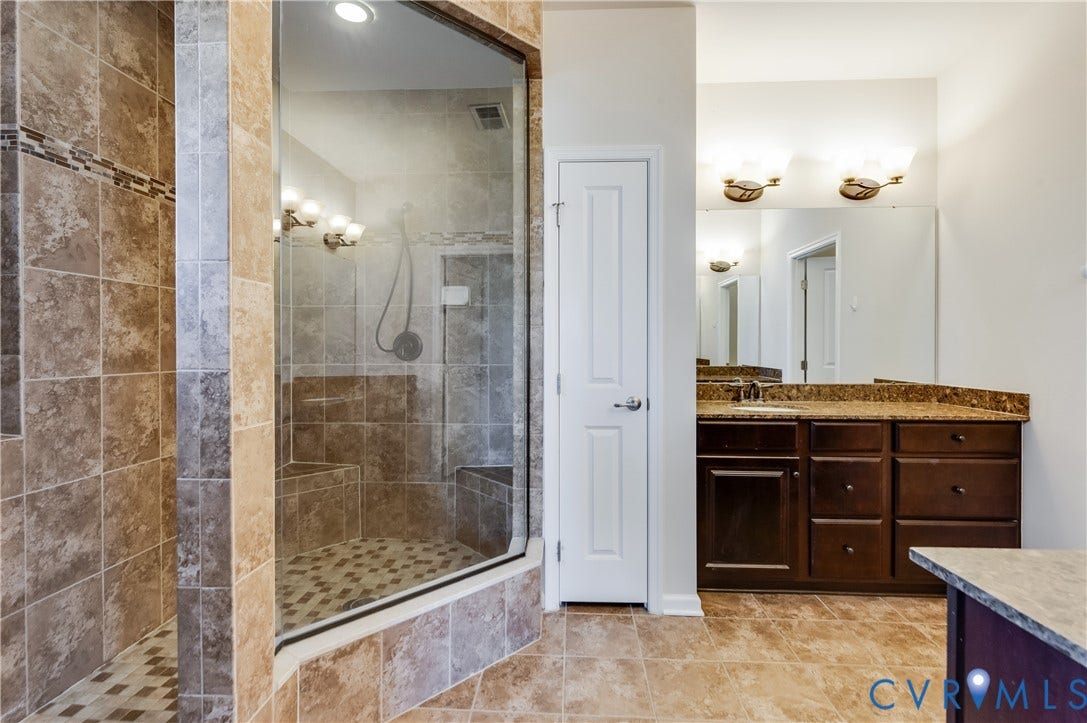 Tiled walk-in shower with a glass enclosure, built-in seating, and a decorative tile accent band