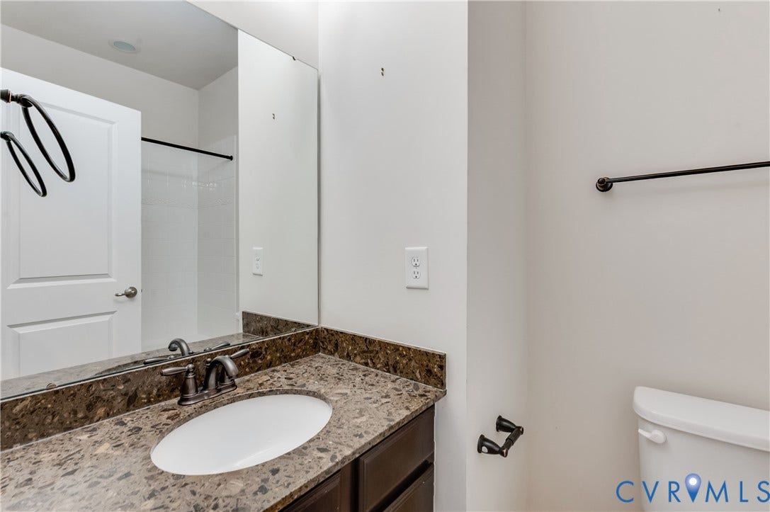 Vanity with an integrated oval sink, dark cabinet, and a stone-finish countertop
