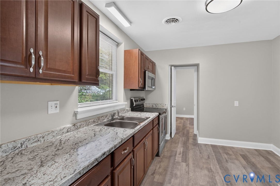 1118 Andros Road, Richmond, VA 23225 Kitchen featuring dark wood cabinetry, light-toned countertops, and a double basin stainless steel sink