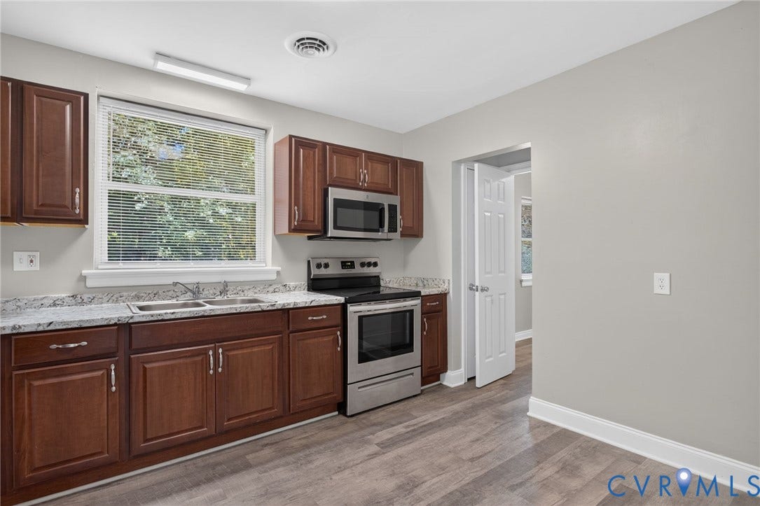 1118 Andros Road, Richmond, VA 23225 Kitchen with new LVP flooring, dark wood cabinetry, light-toned countertops, and stainless steel appliances
