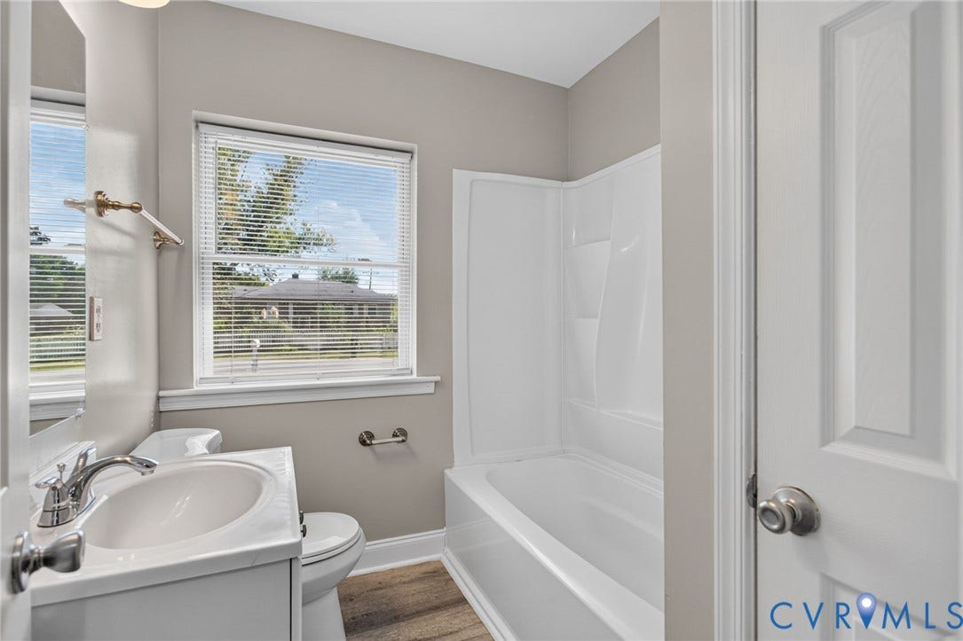 1118 Andros Road, Richmond, VA 23225 Bathroom with a white vanity, a window with blinds, a shower/tub combination, and a white paneled door