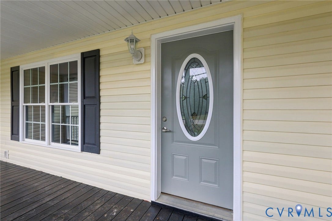 6409 Walmsley Boulevard, Chesterfield, VA 23224 Covered front porch with dark-toned decking, light-colored horizontal siding, dark window shutters, and a front entry door featuring an oval decorative glass insert