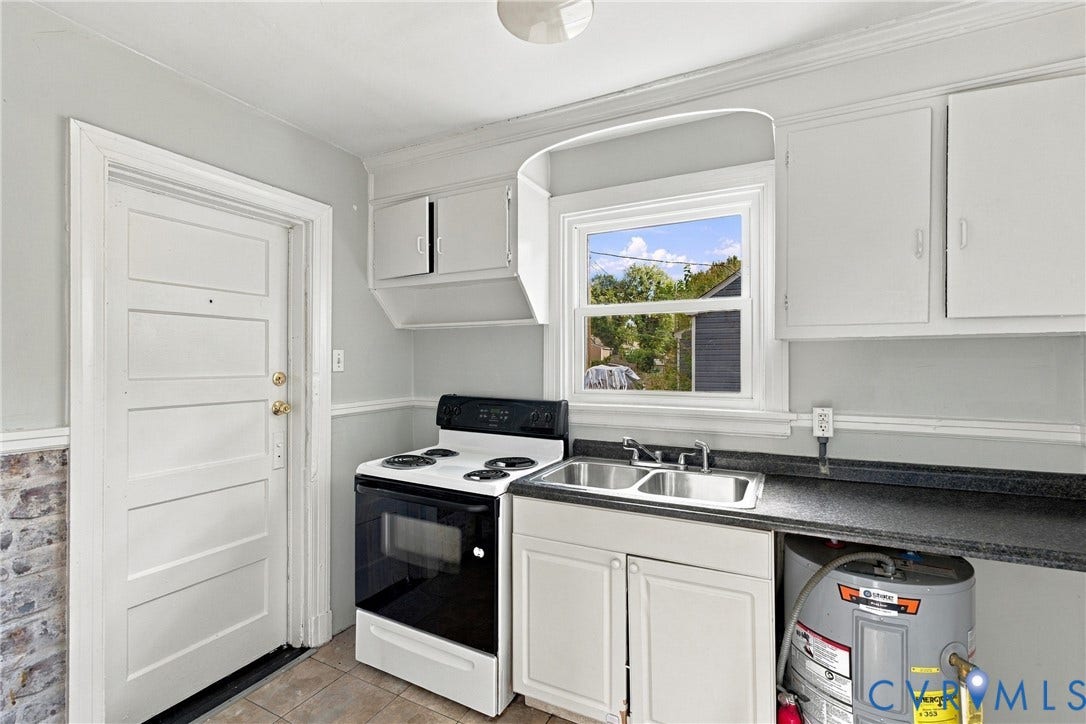 Kitchen with a white paneled door, gray painted walls, and tile flooring