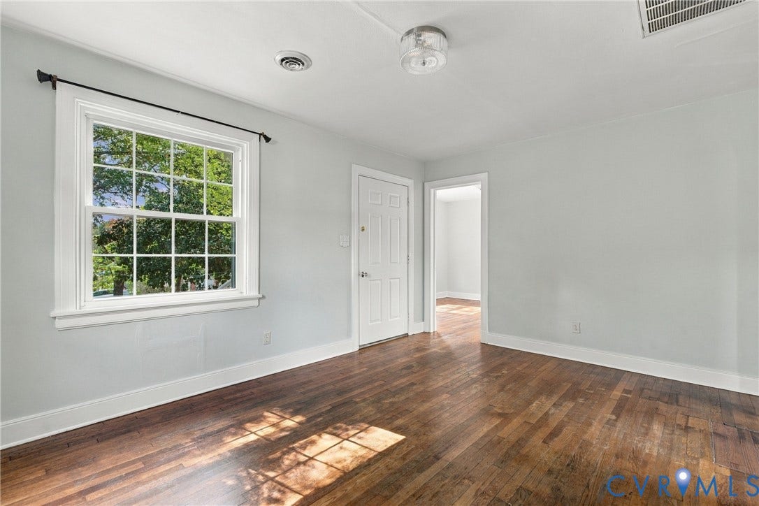 Hardwood flooring, painted walls, white trim, white paneled door, and a white grid window