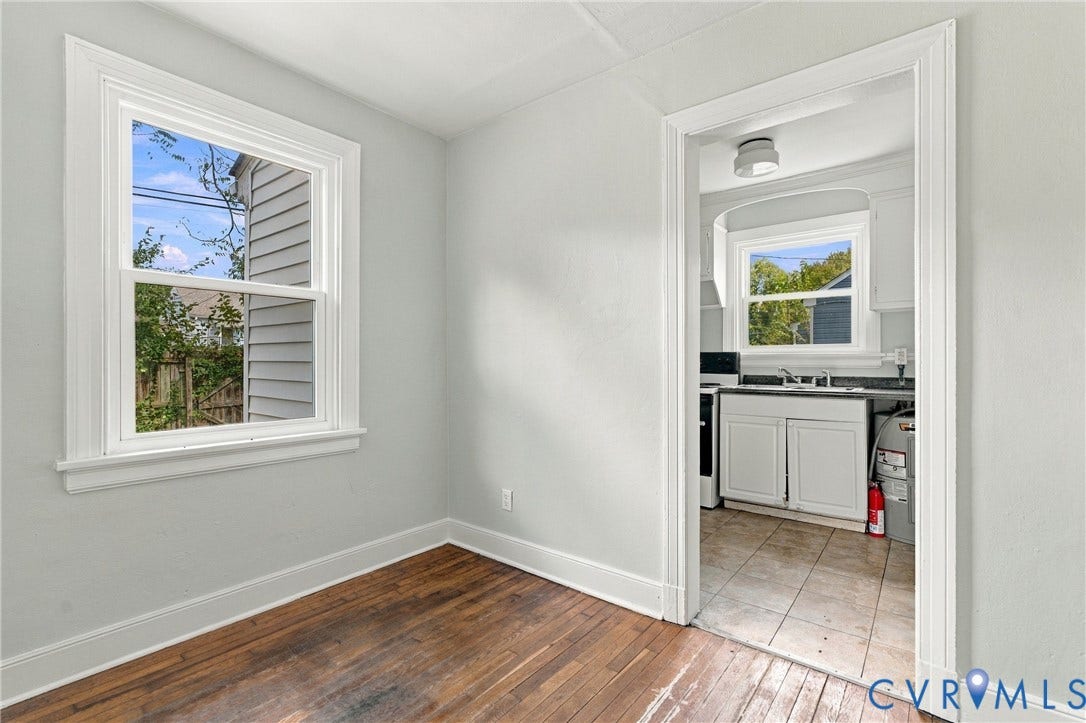 Hardwood flooring, painted interior walls, white trim, white window, and an arched doorway