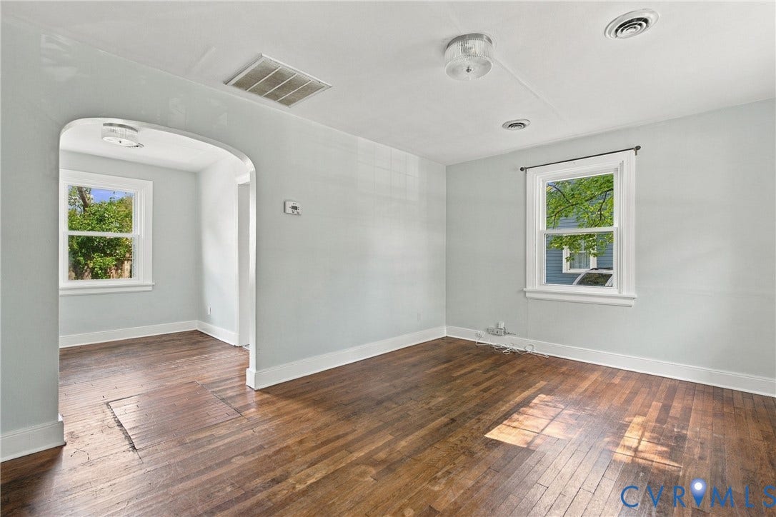 Hardwood flooring, painted walls, white trim, arched doorway, and ceiling-mounted light fixtures
