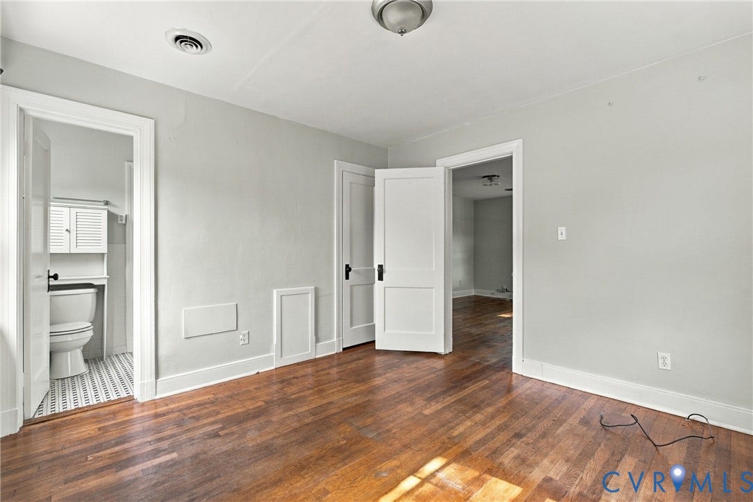 Hardwood-finish flooring, white trim, light-toned walls, and a ceiling-mounted light fixture