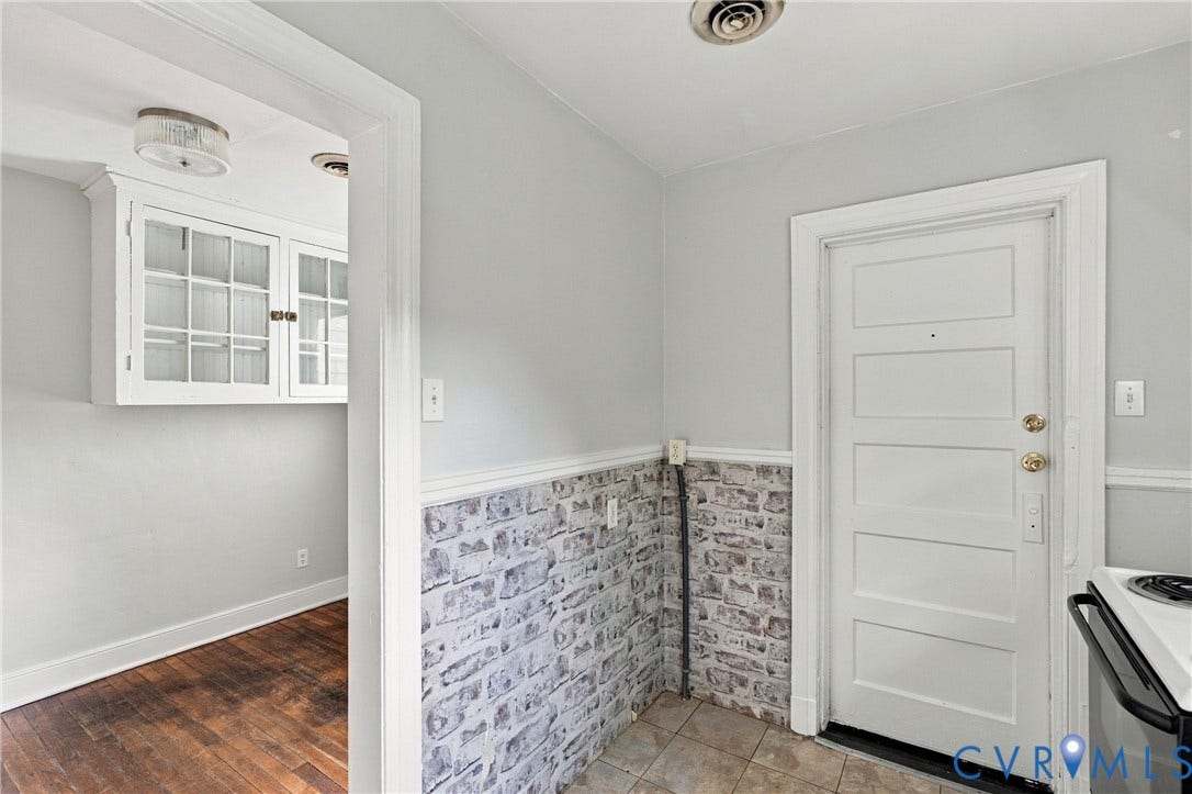 Built-in cabinetry with glass panel doors, wood-finish flooring, and a paneled door with brass hardware