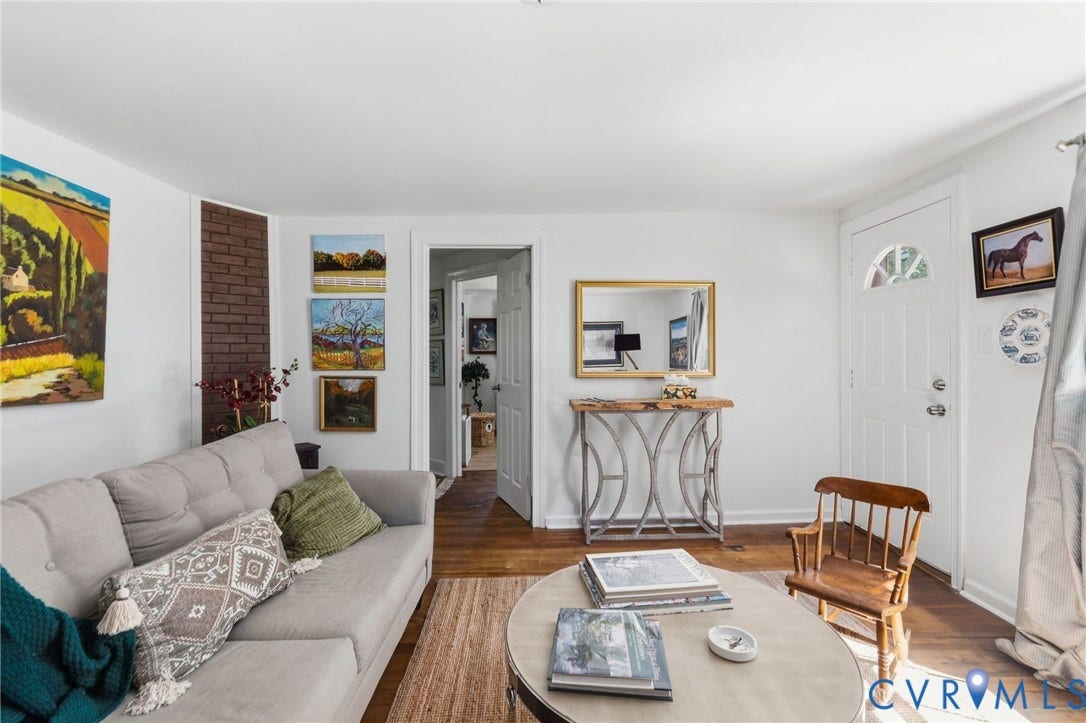Hardwood-finish flooring, white painted trim, and a white entry door with an arched lite.
