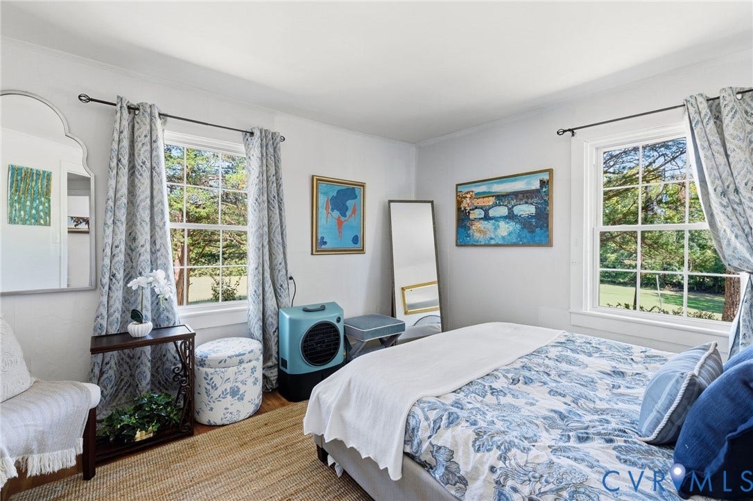 White walls with crown molding, double-hung windows, wood-finish flooring, and a decorative wall mirror.