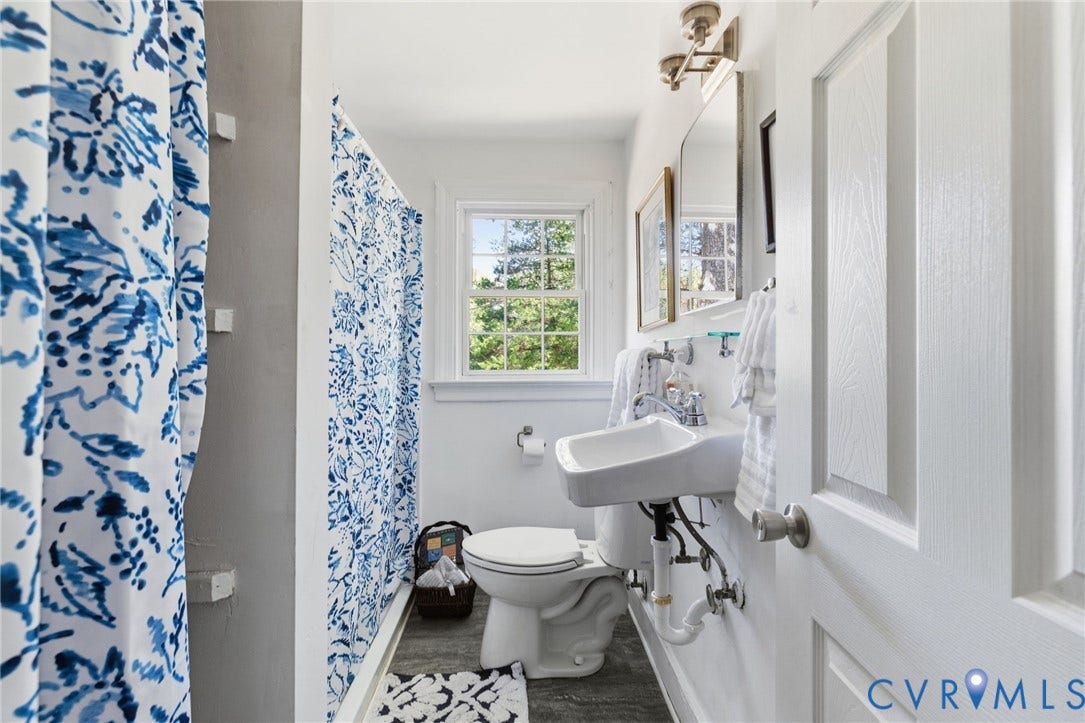White paneled door, wall-mounted sink, window with natural light, and a toilet.