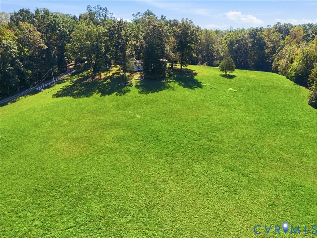 Expansive grassy field with mature trees bordering the perimeter.