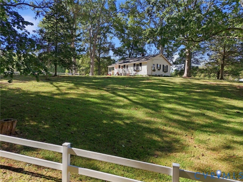 Expansive grassy grounds with mature trees and a white split-rail fence.