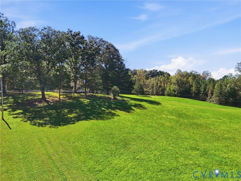 Expansive green lawn with mature trees and a distant tree line.