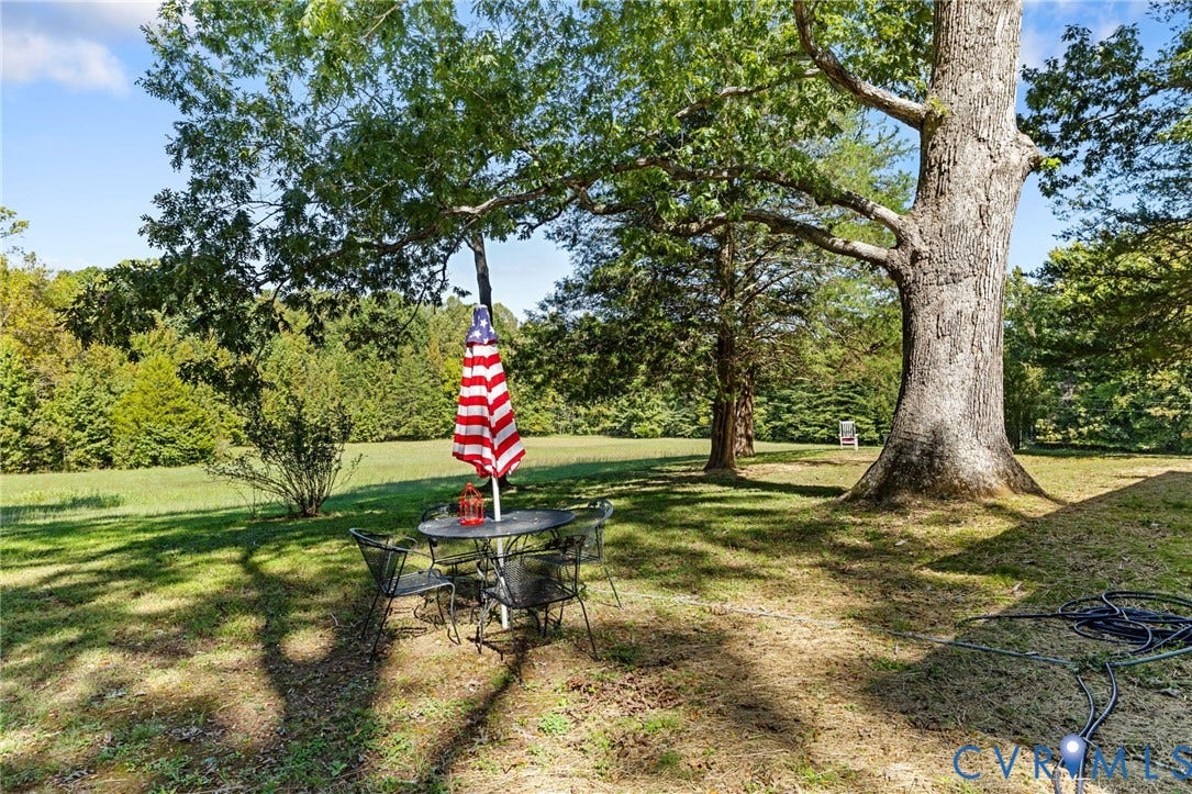 Expansive green space featuring a large mature tree, additional scattered trees, and a distant treeline.