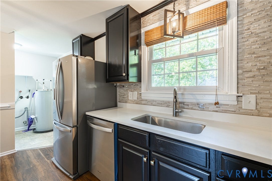 5312 Marian Street, Richmond, VA 23226 Stainless steel appliances, black cabinetry with hardware, white countertops, textured tile backsplash, and wood-finish flooring