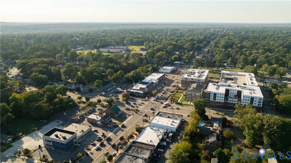 5312 Marian Street, Richmond, VA 23226 Aerial perspective showcasing a mixed-use neighborhood with commercial buildings, multi-story residential structures, extensive tree canopies, and a public park space