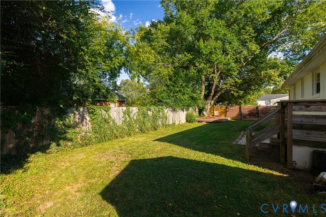 5312 Marian Street, Richmond, VA 23226 Grassed backyard featuring a wooden privacy fence, mature trees, multi-level wooden decking, and exterior siding
