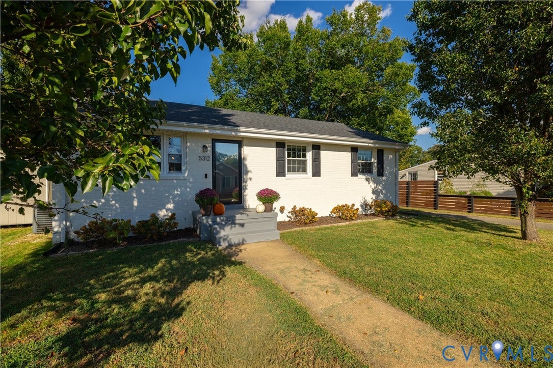 5312 Marian Street, Richmond, VA 23226 White brick exterior with dark shutters, dark roof, front entry with glass door, concrete front steps, and a wooden privacy fence