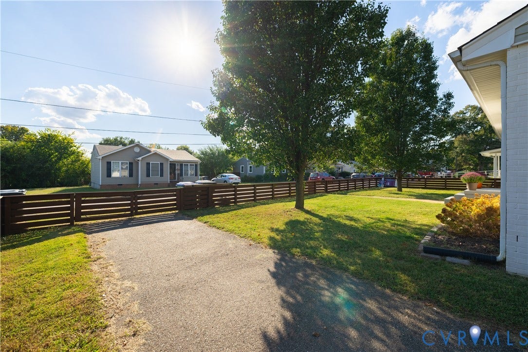 5312 Marian Street, Richmond, VA 23226 Paved driveway leading to a horizontal slat fence, expansive front lawn, and mature trees