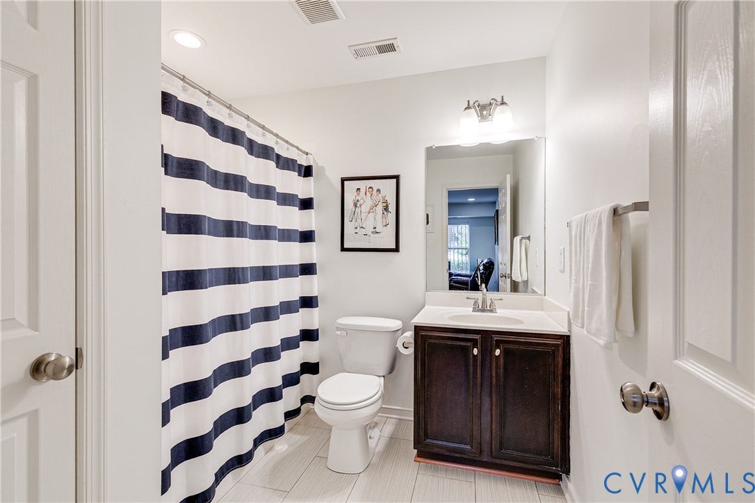 1733 W Cary Street, Richmond, VA 23220 Bathroom featuring a dark wood-finish vanity with a white countertop and an integrated sink, a wall-mounted mirror, and overhead lighting